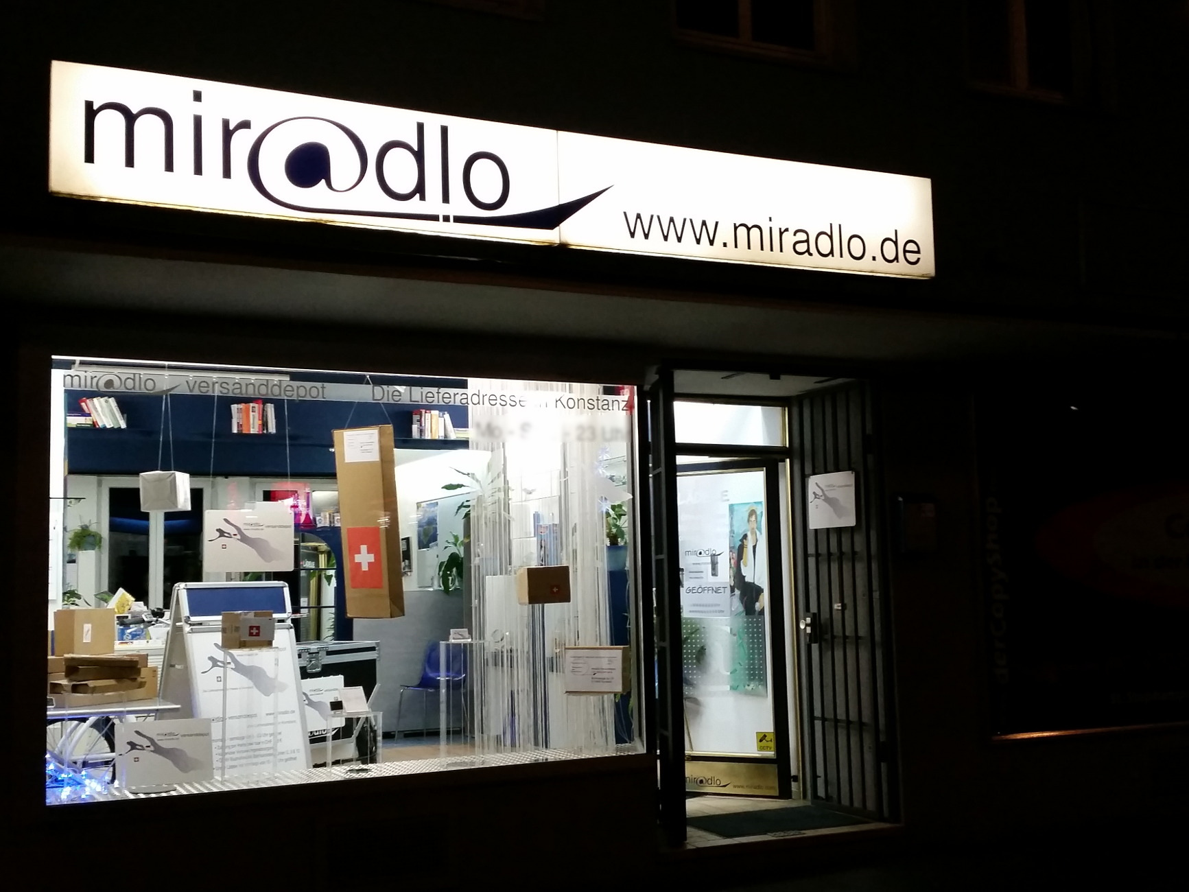 miradlo-Versanddepot - Die Lieferadresse in Konstanz - Schaufenster im Dunkeln mit Paketdekoration