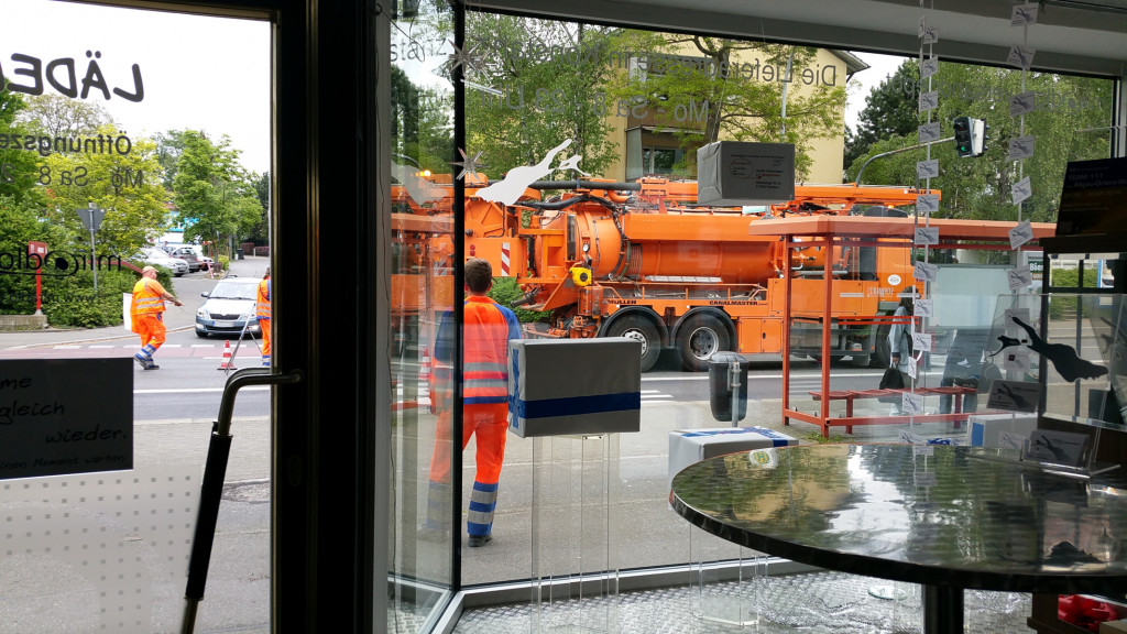 Baufahrzeug vorm Laden durchs Schaufenster fotografiert, miradlo Versanddepot, Lieferadresse Konstanz