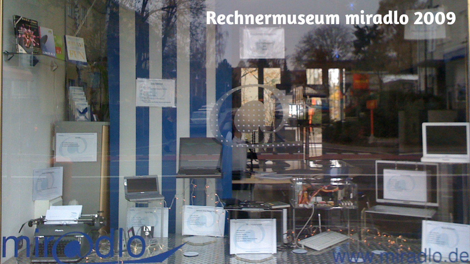 Schaufenster blau-weiß mit diversen Rechnern von mechanischer Schreibmaschine bis 2000-er Laptop als Deko